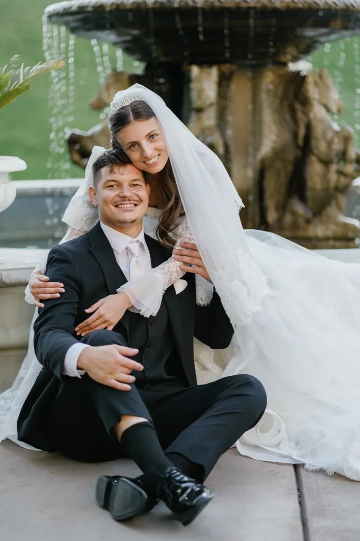 David and his wife smiling by a fountain on their wedding day
