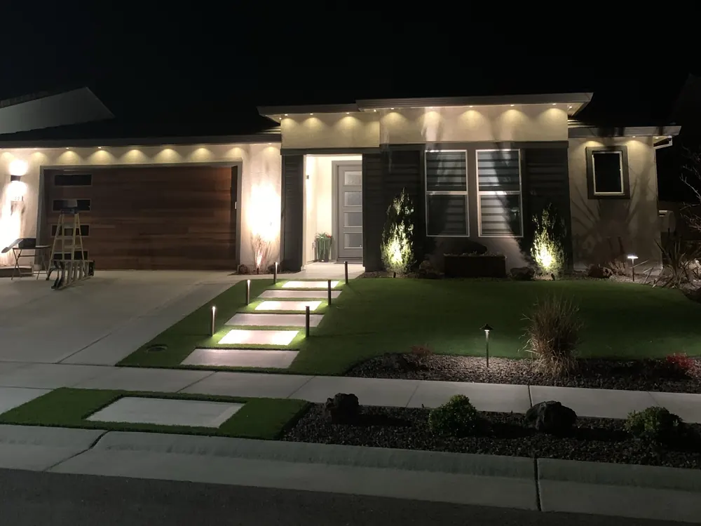 Home with warm white lights along the roofline at night